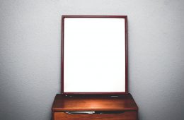 brown wooden dresser with mirror inside white room