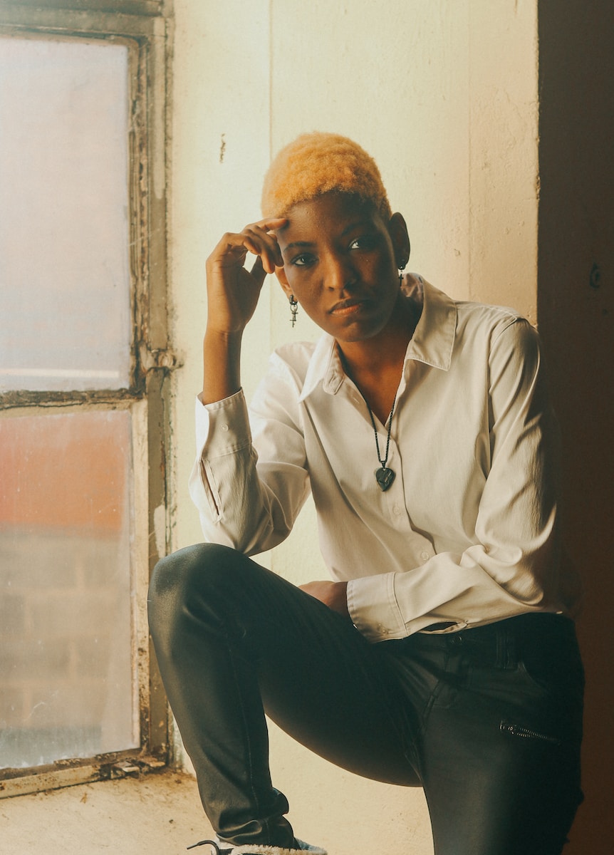 man in white dress shirt and black pants sitting on window