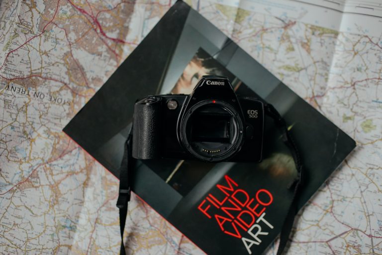 black Canon DSLR camera on top of black book