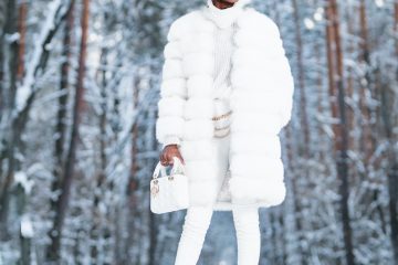 woman in white coat standing on snow covered ground