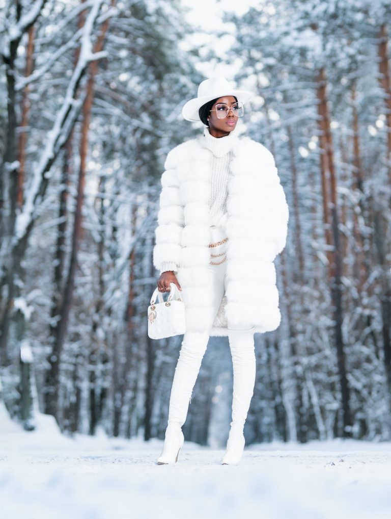 woman in white coat standing on snow covered ground