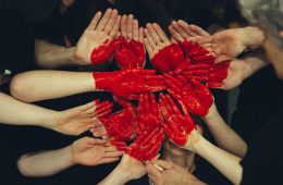 hands formed together with red heart paint