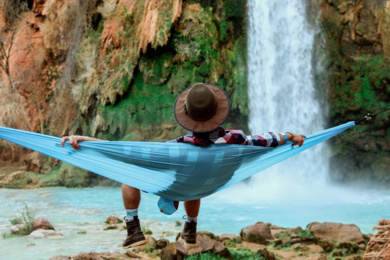 man lying on hammock near waterfalls
