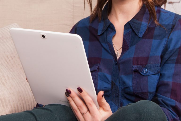 woman in blue denim button up jacket holding white laptop computer