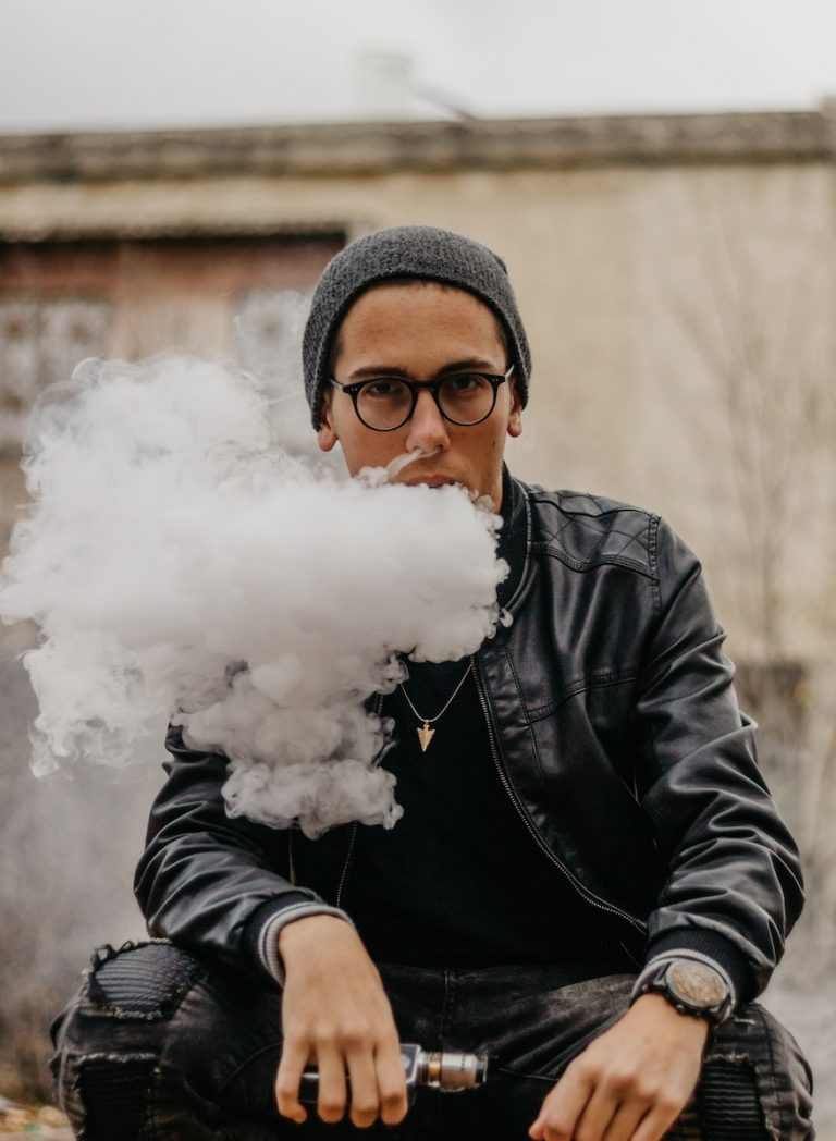 man sitting while vaping in selective focus photography