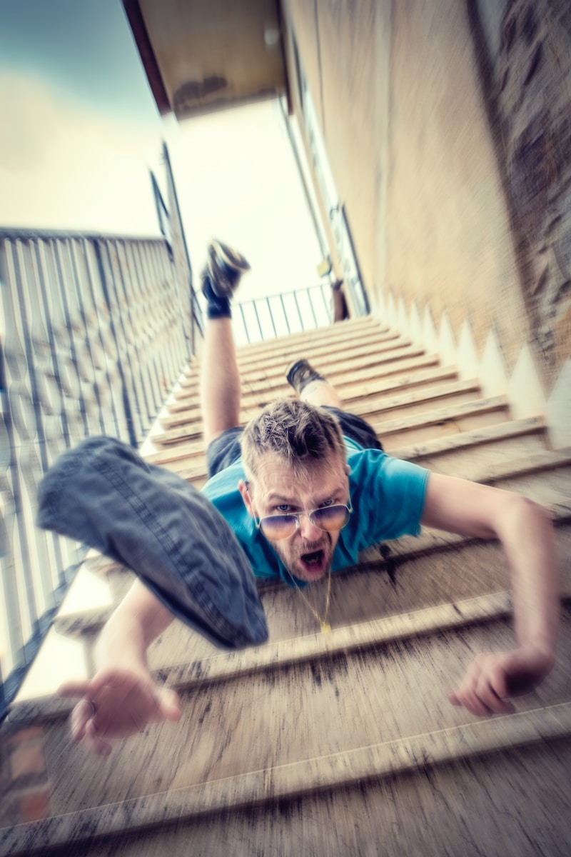 man in blue t-shirt and blue denim shorts sitting on concrete stairs during daytime