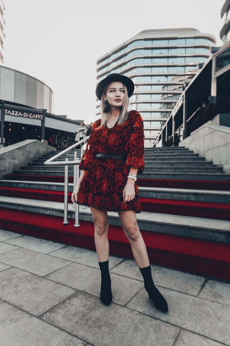 woman in red and black floral dress standing near stairs