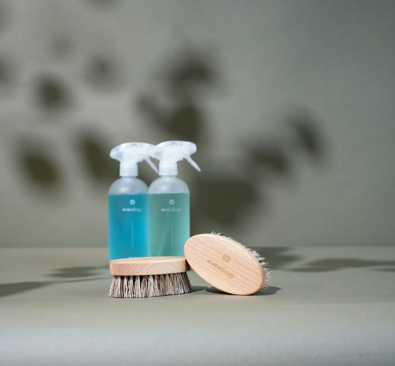 a wooden brush and two bottles of cleaner on a table