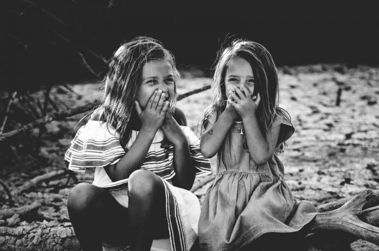 grayscale photography of two girls closing their mouths